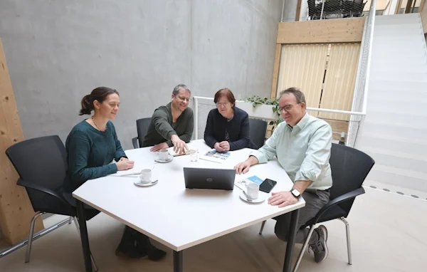 Drei Personen stehen auf einem Weg im Freien und besprechen etwas.