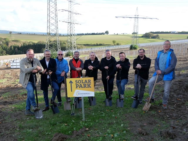 Mehrere Männer stehen mit Spaten vor einem Schild mit Aufschrift Solarpark