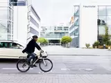Radfahrer und Auto vor urbanem Hintergrund