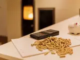 Tisch mit Holzpellets und Taschenrechner, im Hintergrund ein Kamin