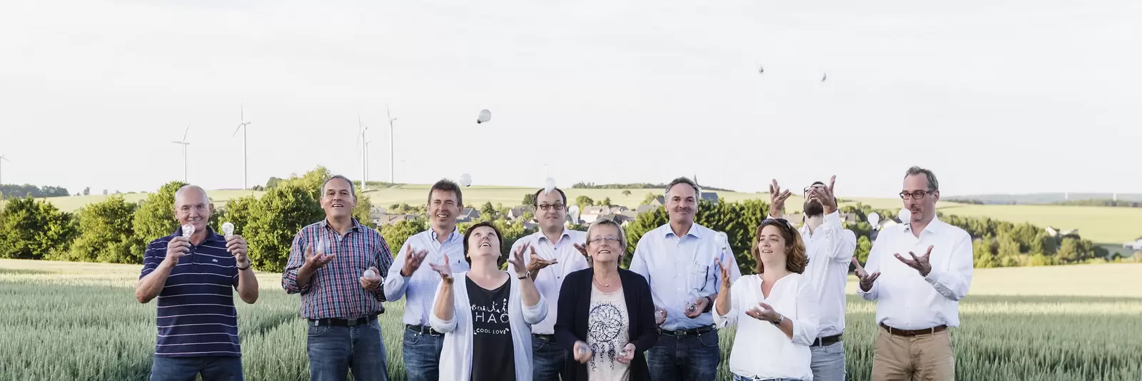 Mehrere Menschen stehen auf einem Feld und werfen Glühbirnen in die Luft