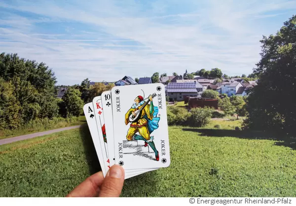Joker im Kartendeck mit Häusern im Hintergrund auf denen PV-Anlagen angebracht sind