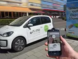 E-Carsharing-Fahrzeug und Smartphone mit geöffneter Carsharing-App im Vordergrund