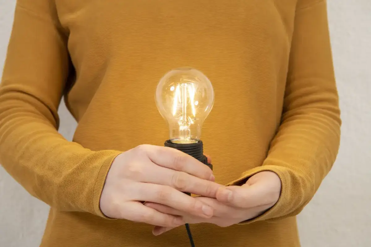 Eine Person hält eine leuchtende Glühbirne in der Hand