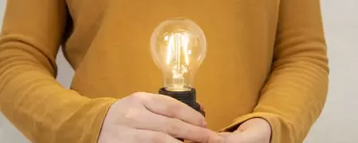 Eine Person hält eine leuchtende Glühbirne in der Hand