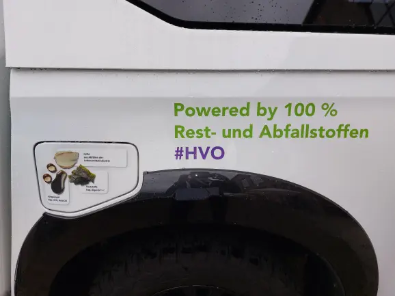 Auf einem Fahrzeug steht der Schriftzug "powered by 100 % Rest- und Abfallstoffen"