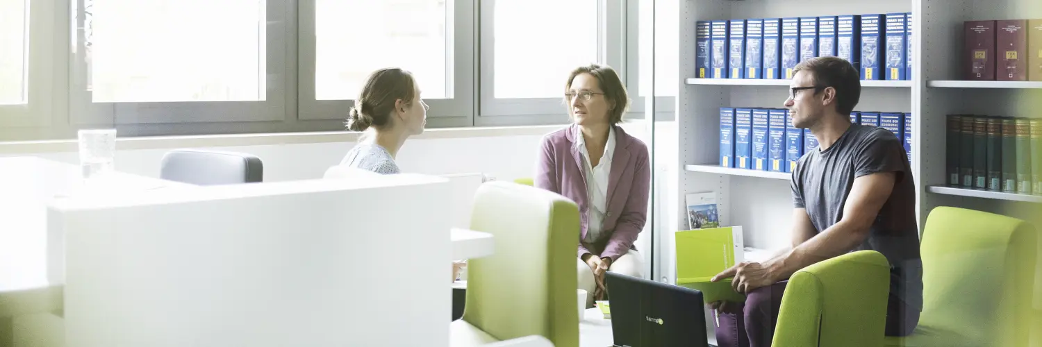 Drei Personen unterhalten sich in einem Besprechungsraum